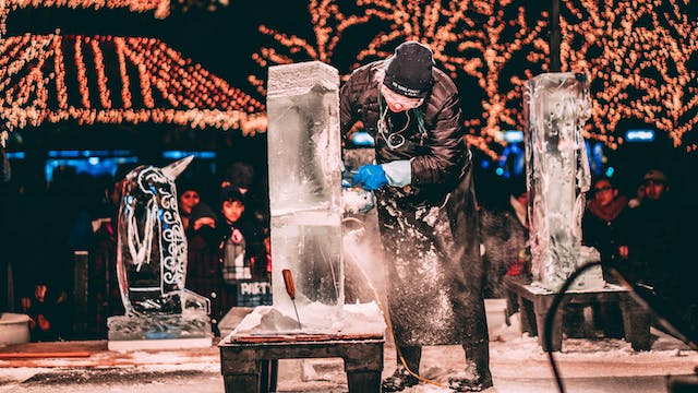 Ice sculpture festivals. Man making ice sculpture with fairy lights in backgrounder